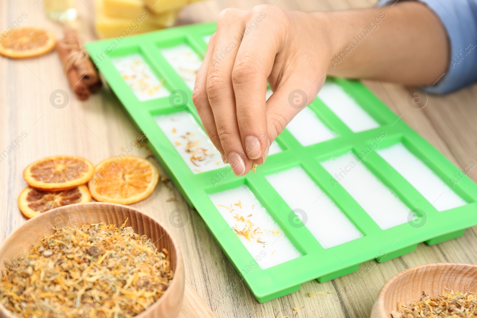 Photo of Woman making natural handmade soap at wooden table, closeup