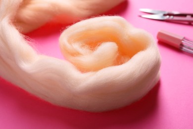 Beige felting wool on pink background, closeup