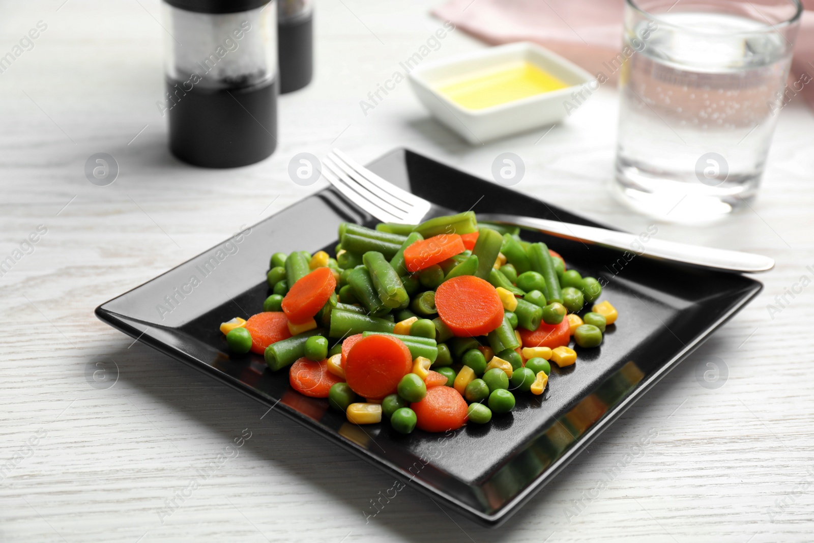 Photo of Plate with tasty vegetable salad on white wooden table