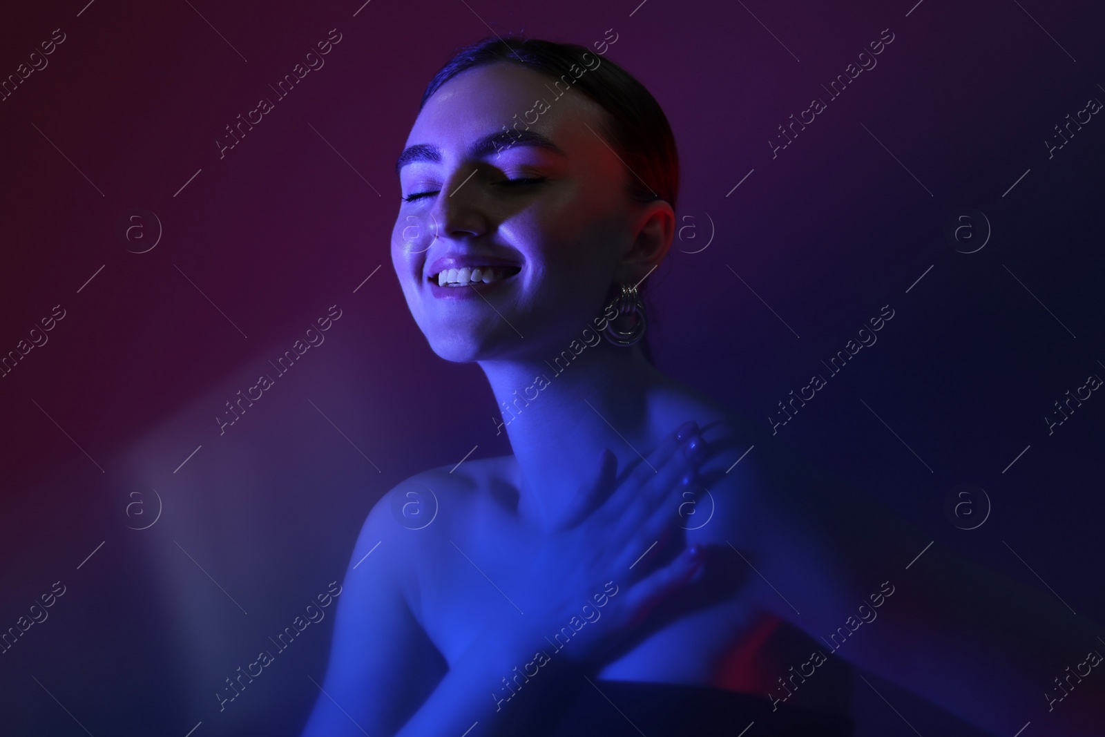 Photo of Portrait of beautiful young woman on color background in neon lights