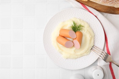 Delicious boiled sausages and mashed potato on white tiled table, top view. Space for text
