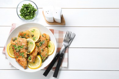 Photo of Delicious chicken piccata served on white wooden table, flat lay. Space for text