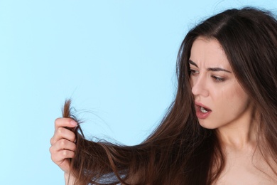 Photo of Emotional woman with damaged hair and space for text on color background. Split ends