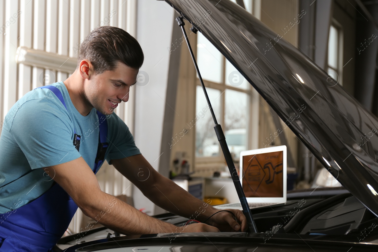 Photo of Mechanic with laptop doing car diagnostic at automobile repair shop