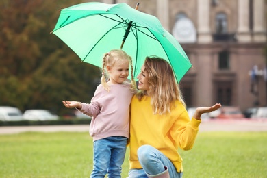 Happy mother and daughter with umbrella in park