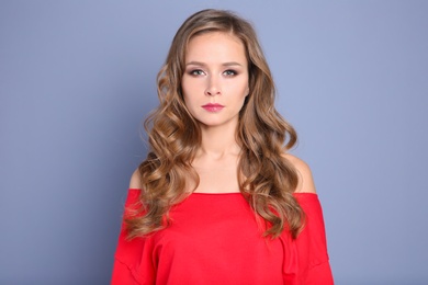 Portrait of young woman with long beautiful hair on grey background