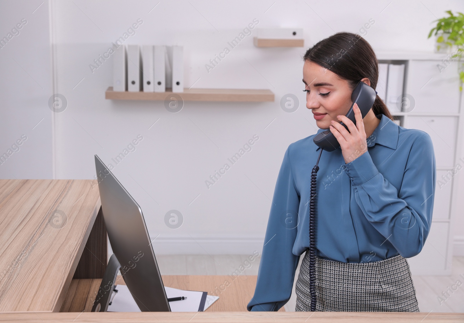 Photo of Female receptionist talking on phone at workplace