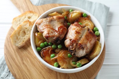 Photo of Tasty cooked rabbit with vegetables in bowl on white wooden table, closeup