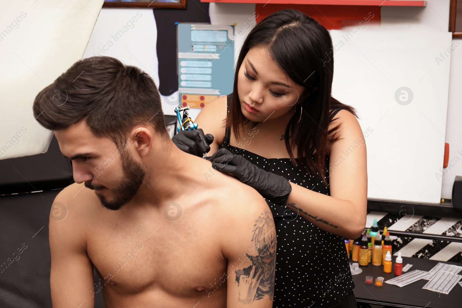 Photo of Professional artist making tattoo with machine in salon