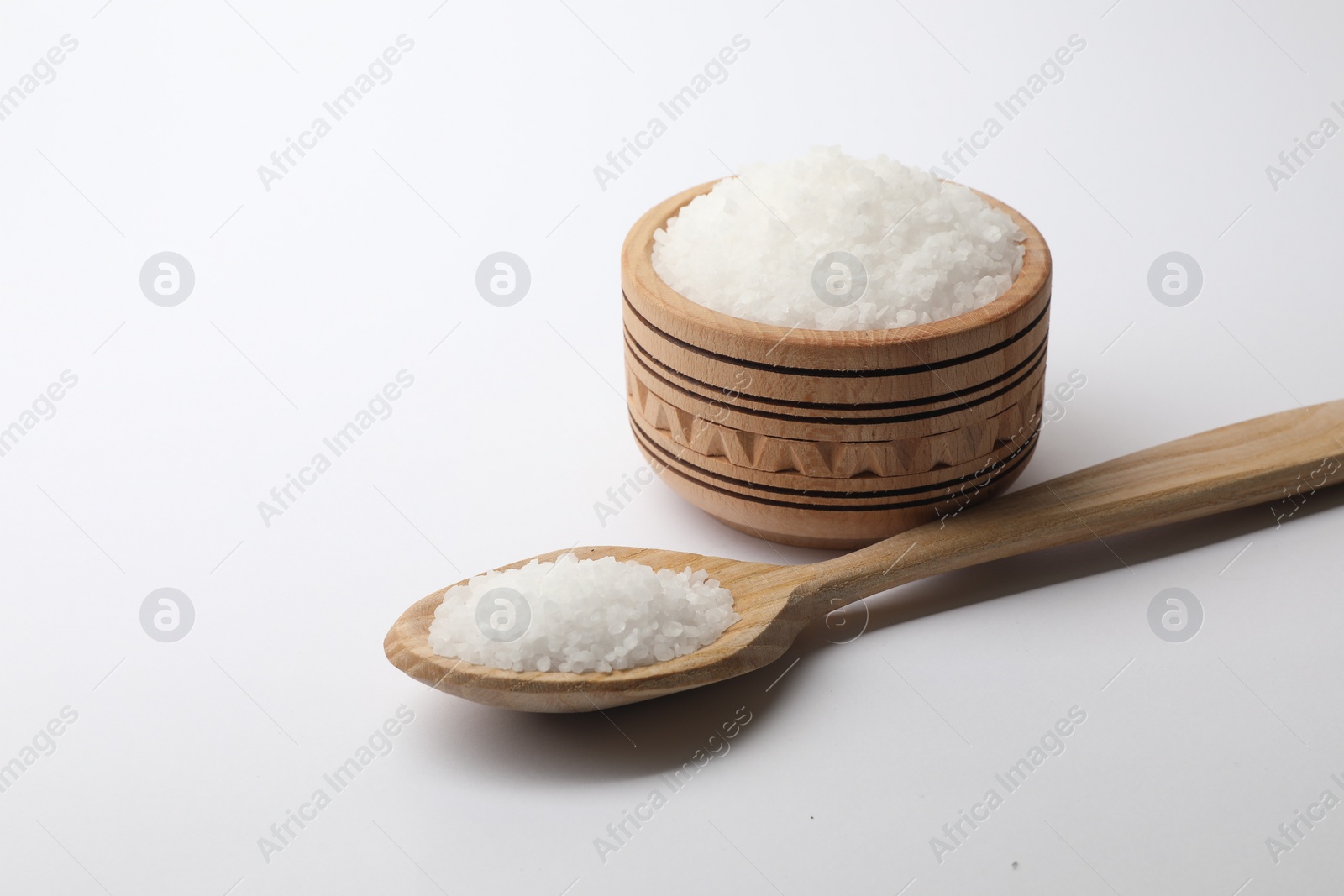 Photo of Natural salt in wooden spoon and bowl on white background