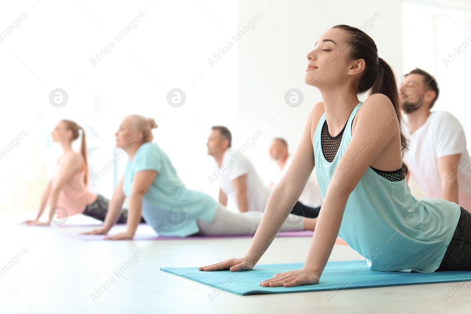 Photo of Group of people in sportswear practicing yoga indoors