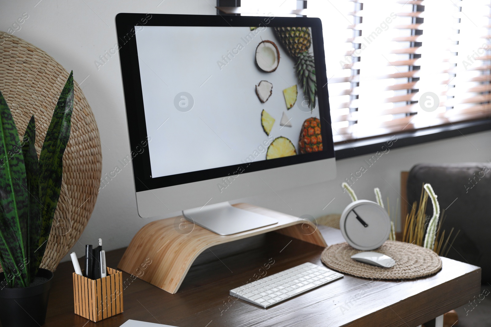 Photo of Comfortable workplace near window with horizontal blinds in room