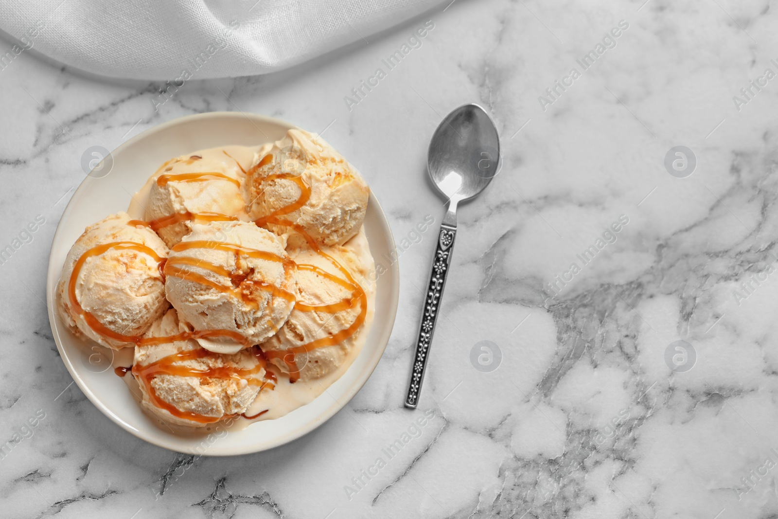 Photo of Tasty ice cream with caramel sauce on plate, top view