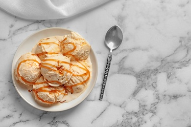 Photo of Tasty ice cream with caramel sauce on plate, top view