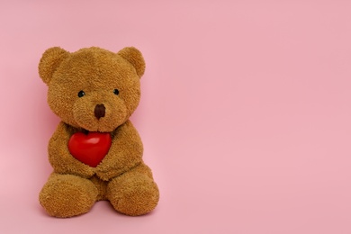 Photo of Cute teddy bear with red heart on pink background, space for text. Valentine's day celebration