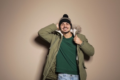 Young man wearing warm clothes on color background. Ready for winter vacation