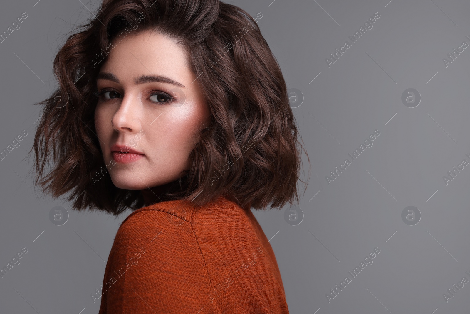 Photo of Portrait of beautiful young woman with wavy hairstyle on grey background. Space for text