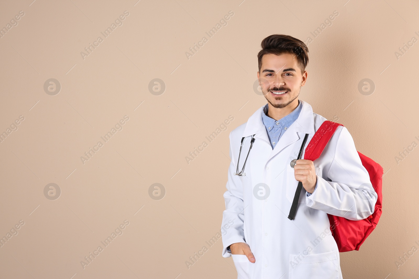 Photo of Young medical student with backpack on color background. Space for text