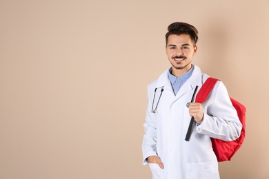 Young medical student with backpack on color background. Space for text