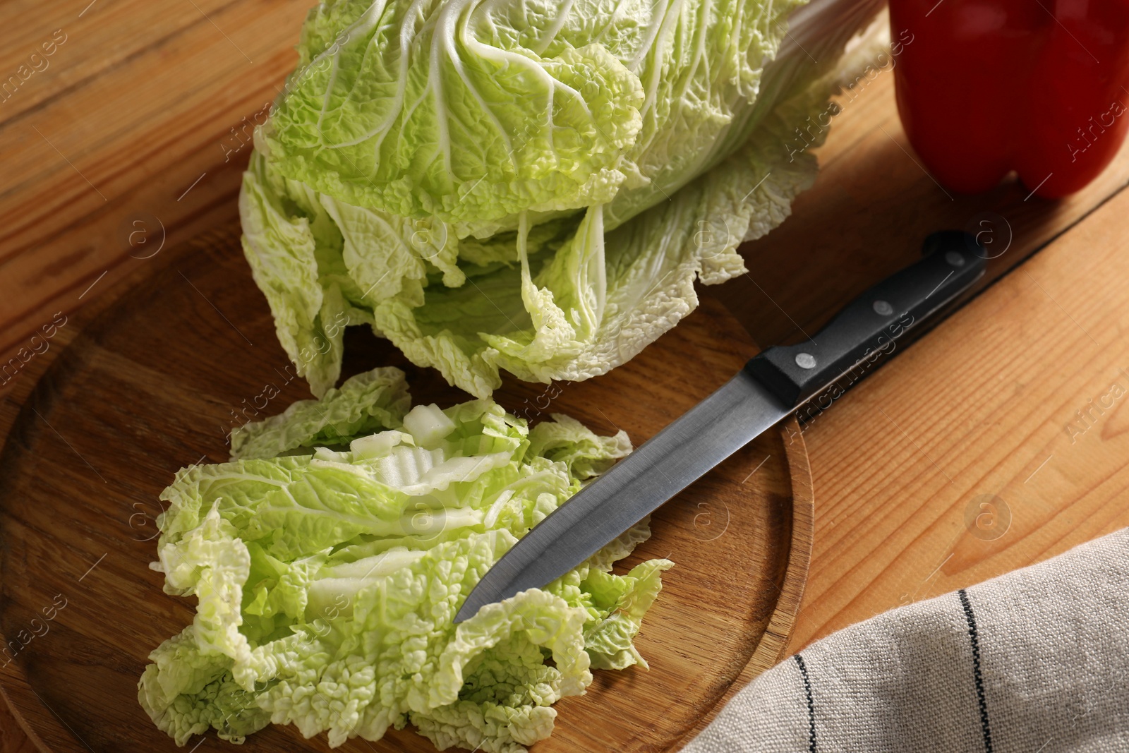 Photo of Fresh Chinese cabbage, pepper and knife on wooden table, closeup