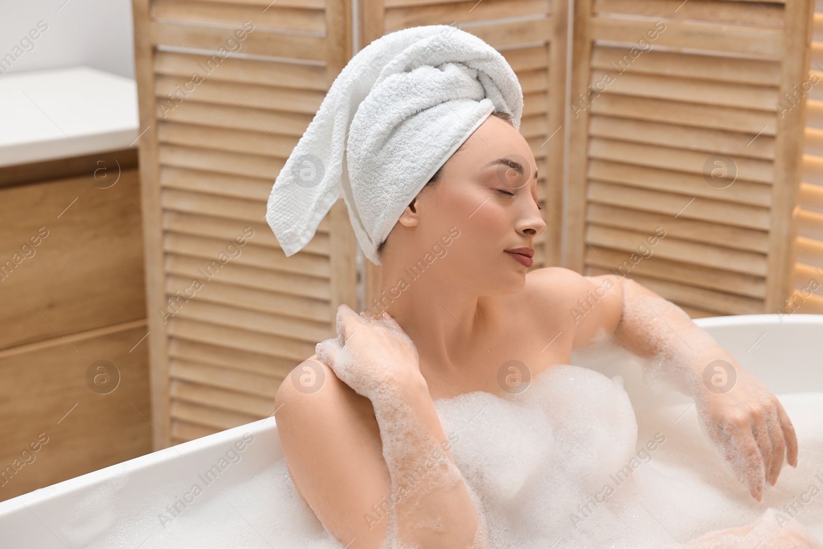 Photo of Beautiful woman taking bath with foam in tub indoors, space for text