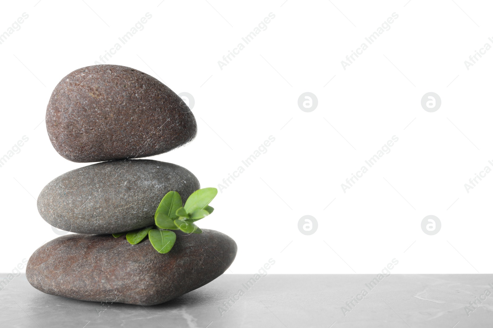 Photo of Stack of spa stones and green leaves on table against white background. Space for text