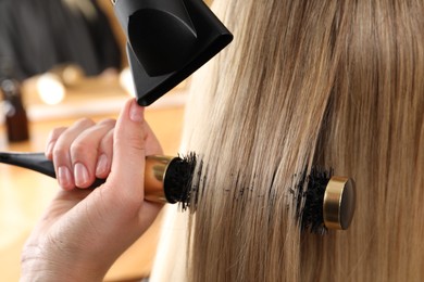 Photo of Hairdresser blow drying client's hair in salon, closeup