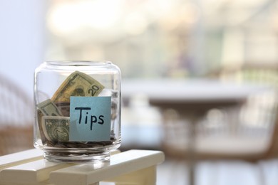 Glass jar with tips on table indoors. Space for text