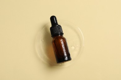 Bottle of cosmetic serum on beige background, top view