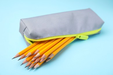 Many sharp pencils in pencil case on light blue background