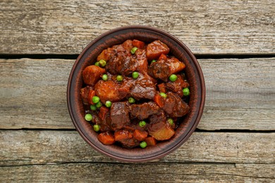 Photo of Delicious beef stew with carrots, peas and potatoes on wooden table, top view