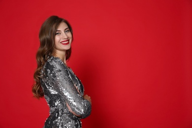 Photo of Happy woman in silver shiny dress on red background, space for text. Christmas party
