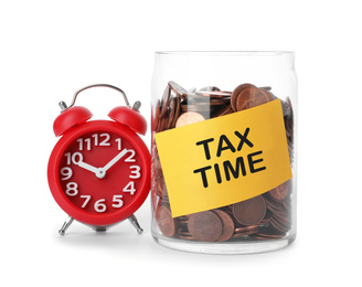 Time to pay taxes. Coins in glass jar with label and alarm clock on white background