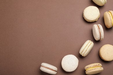 Photo of Delicious colorful macarons on brown background, flat lay. Space for text