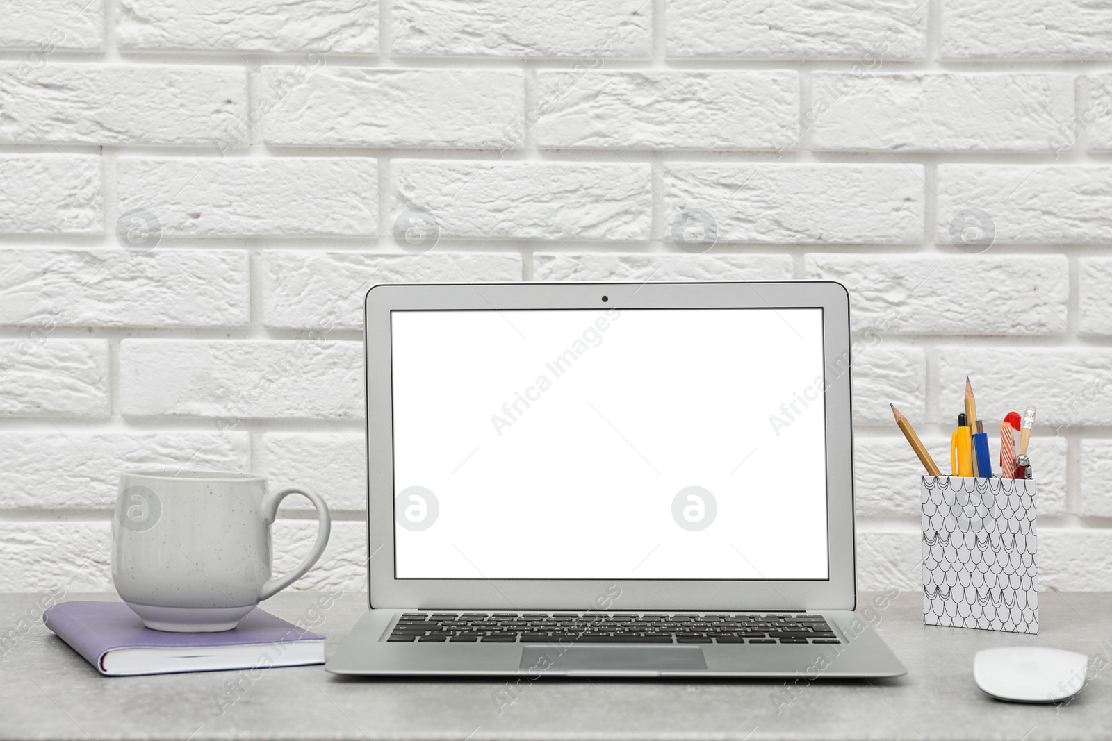 Photo of Laptop on desk against brick wall in home office. Comfortable workplace