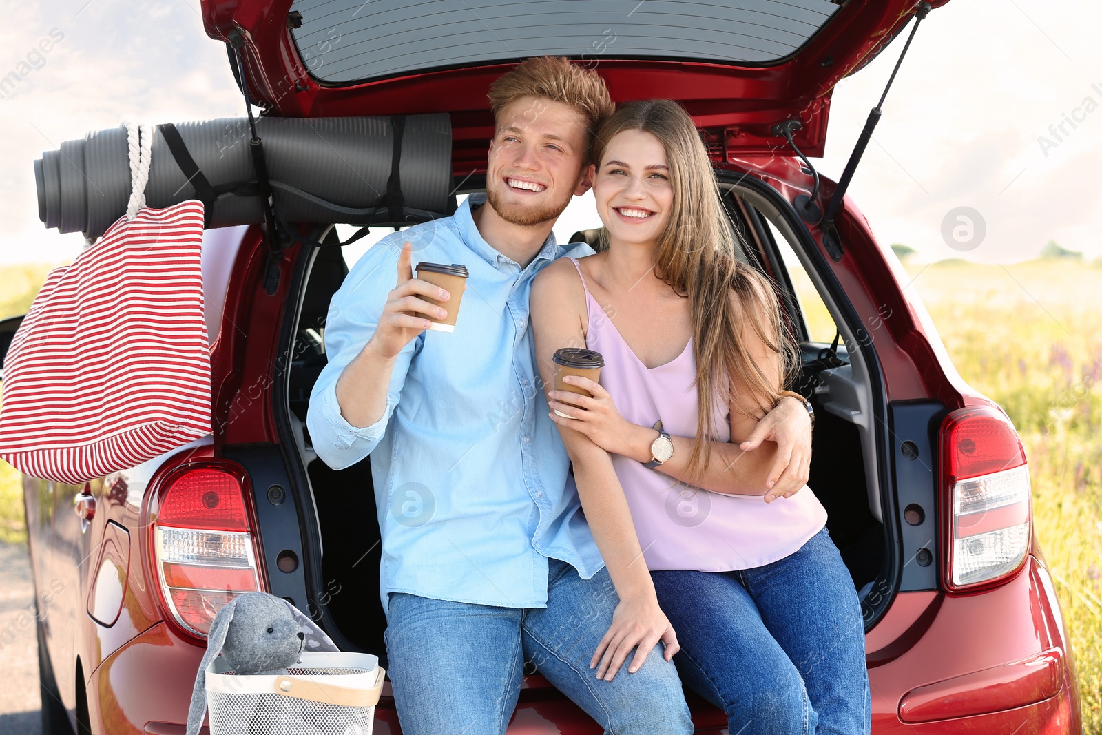 Photo of Young couple with luggage near car trunk outdoors