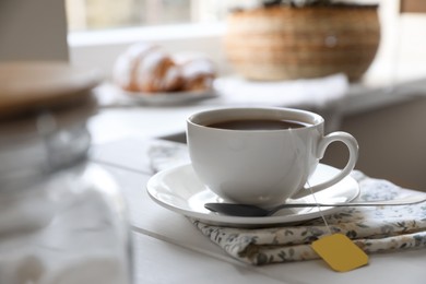 Photo of Tea bag in cup on white wooden table indoors. Space for text