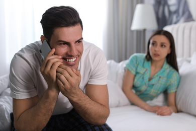 Photo of Distrustful young woman eavesdropping on boyfriend at home. Jealousy in relationship