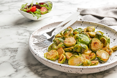 Photo of Delicious roasted brussels sprouts on white marble table