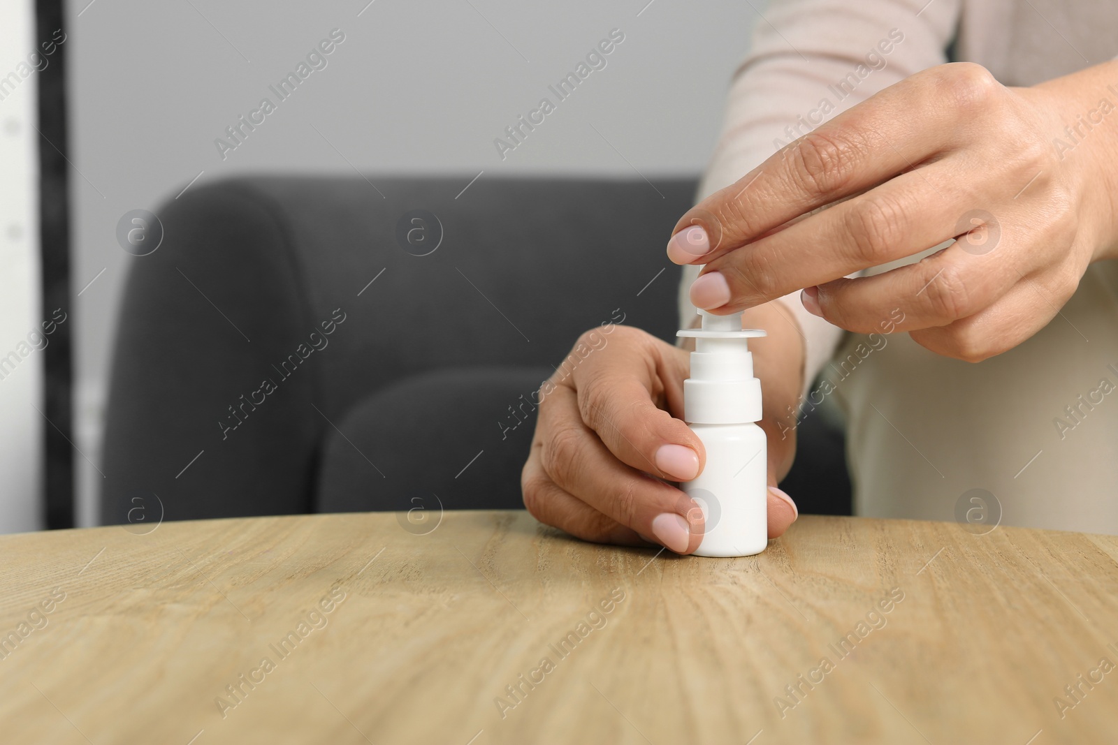 Photo of Woman opening nasal spray at wooden table indoors, closeup. Space for text