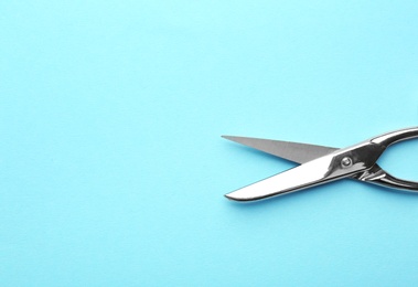 Photo of Pair of sharp scissors on color background, top view. Space for text