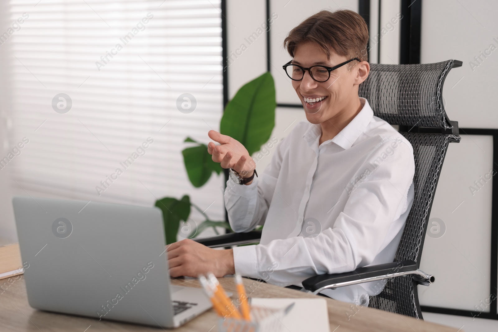 Photo of Man using video chat during webinar at wooden table in office