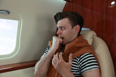 Photo of Nervous young man in airplane. Aviophobia concept