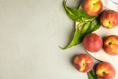 Flat lay composition with fresh peaches and leaves on grey stone surface, space for text