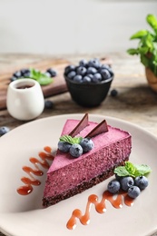 Plate with piece of tasty blueberry cake on table