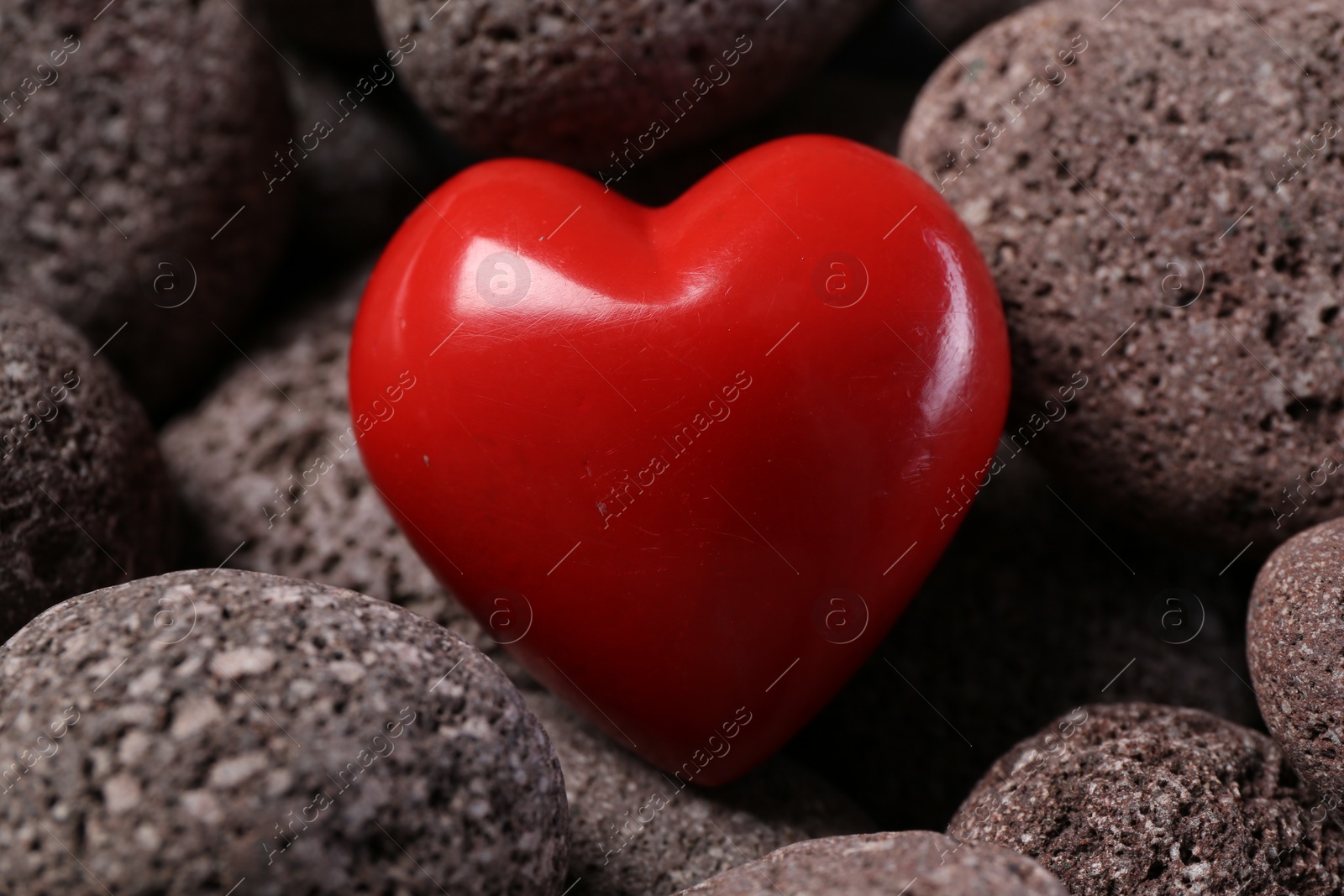 Photo of One red decorative heart on stones, closeup