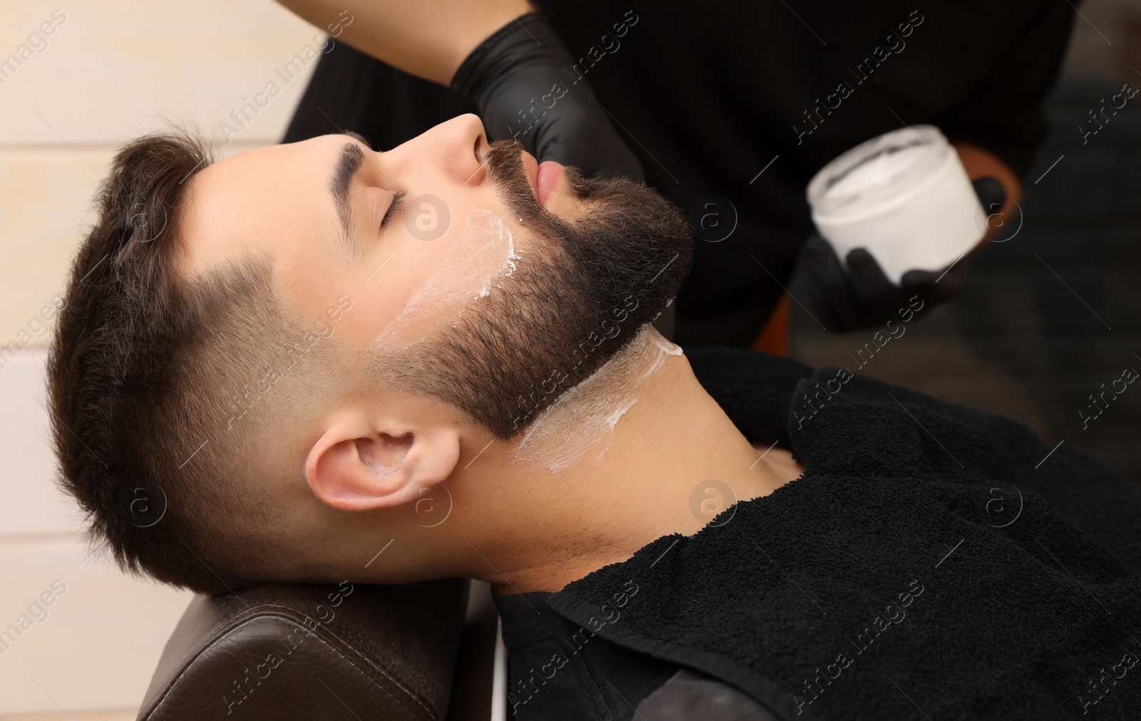 Photo of Professional hairdresser working with client in barbershop, closeup