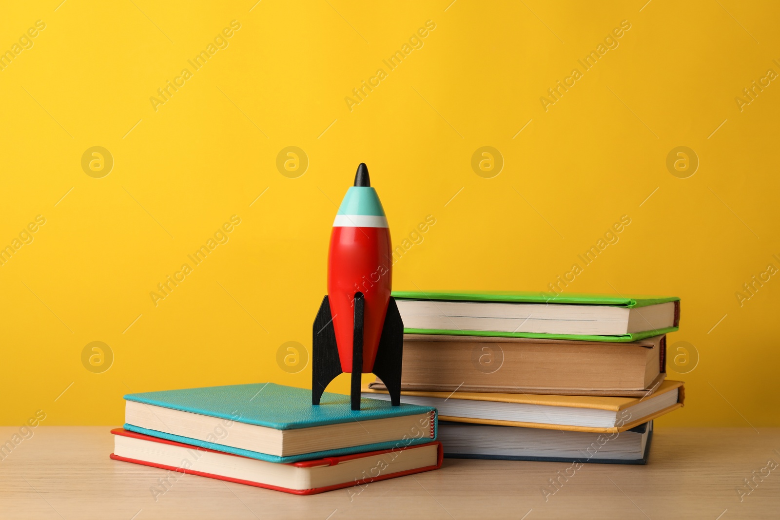 Photo of Bright toy rocket and school supplies on wooden table