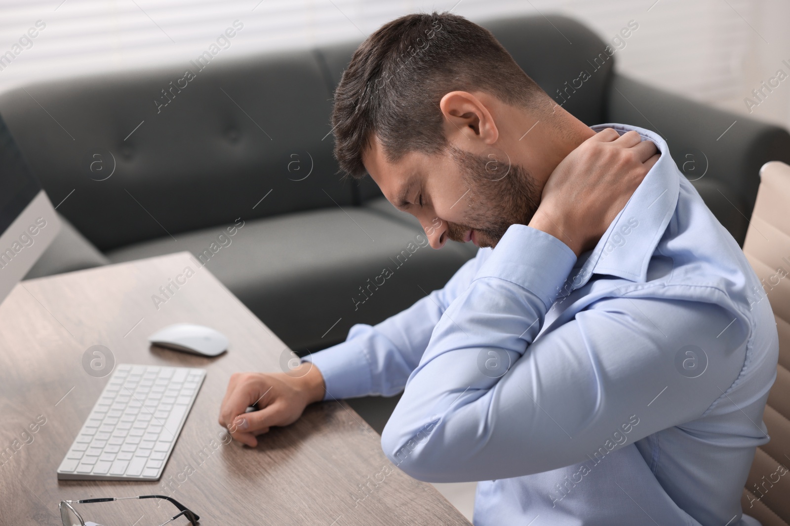 Photo of Man suffering from neck pain in office