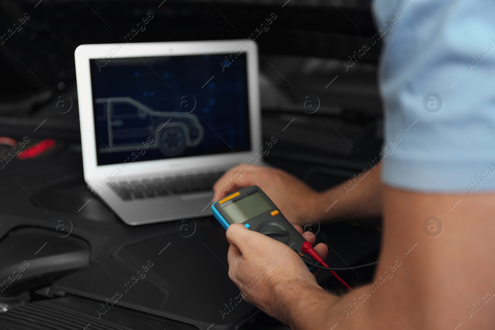 Photo of Mechanic with laptop doing car diagnostic at automobile repair shop, closeup